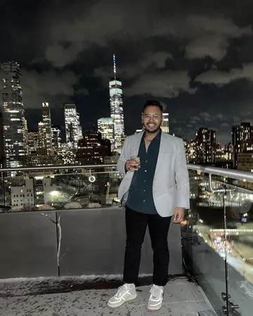 Shiv on a rooftop at night with the Manhattan skyline behind him